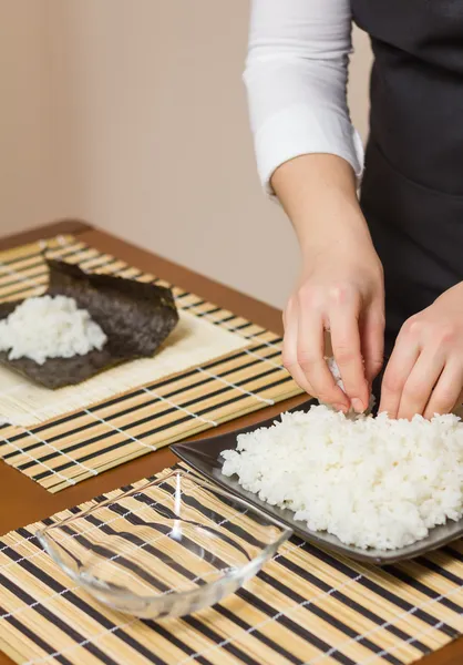 Woman chef filling japanese sushi rolls with rice — Stock Photo, Image