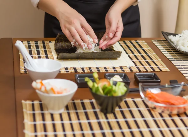 Mujer chef llenando rollos de sushi japonés con arroz —  Fotos de Stock