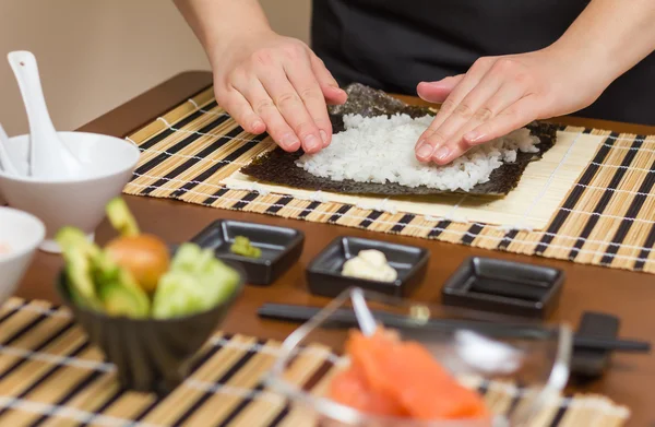 Mujer chef llenando rollos de sushi japonés con arroz —  Fotos de Stock