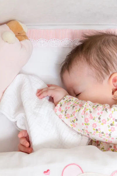 Emzik ve oyuncak bir karyolası uyuyan kız bebek — Stok fotoğraf