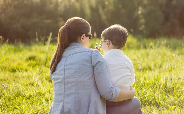 Son giving bouquet of flowers to mother in field — Stock Photo, Image