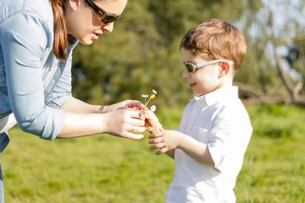 Filho dando buquê de flores para a mãe no campo — Fotografia de Stock