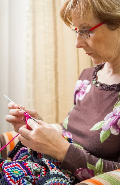 Portrait of woman knitting a vintage wool quilt — Stock Photo, Image