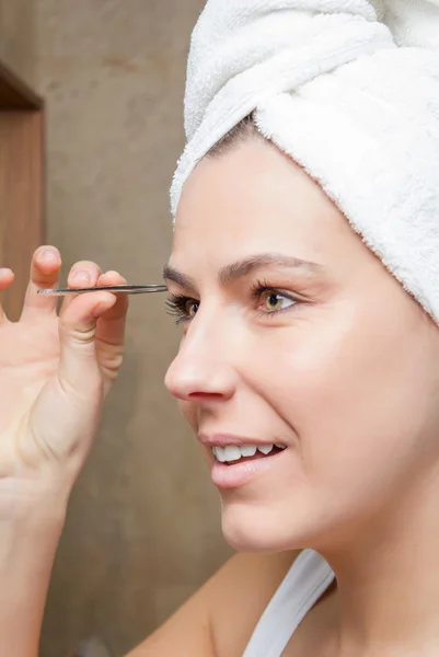 Portrait of girl plucking eyebrows with tweezers — Stock Photo, Image