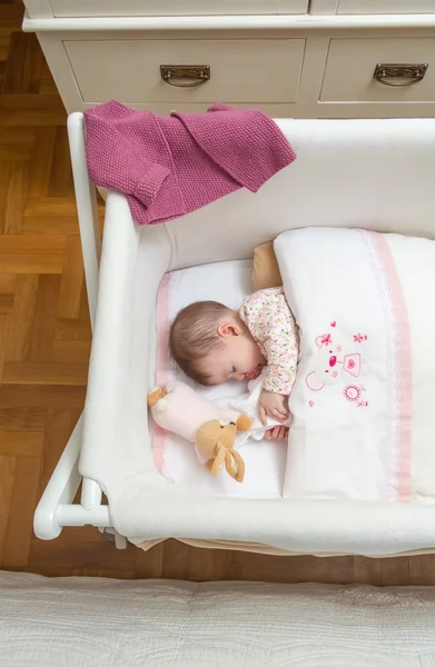 Meisje van de baby slapen in een kinderbed met fopspeen en speelgoed — Stockfoto