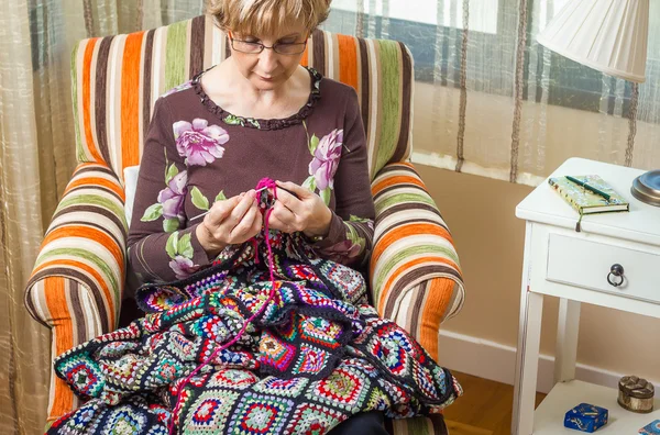 Portrait of woman knitting a vintage wool quilt