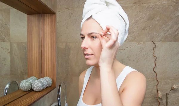 Portrait of girl plucking eyebrows with tweezers — Stock Photo, Image