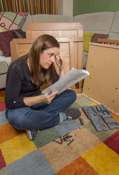Dívka čtení instrukce k sestavení nábytku — Stock fotografie