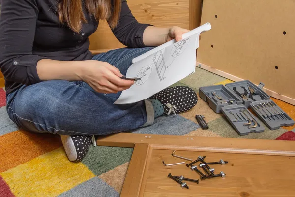 Mädchen liest Anleitung zum Zusammenbau von Möbeln — Stockfoto