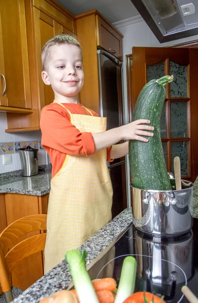 Cute child chef cooking big zucchini in a pot — Stock Photo, Image
