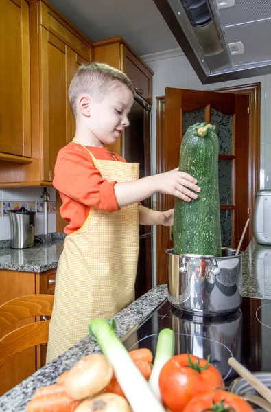 Cute chef criança cozinhar abobrinha grande em uma panela — Fotografia de Stock