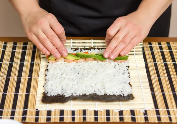 Händerna på kvinna kock rullar upp en japansk sushi — Stockfoto