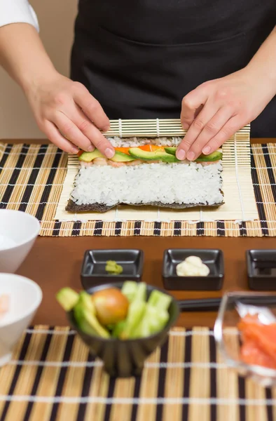 Manos de mujer chef enrollando un sushi japonés — Foto de Stock