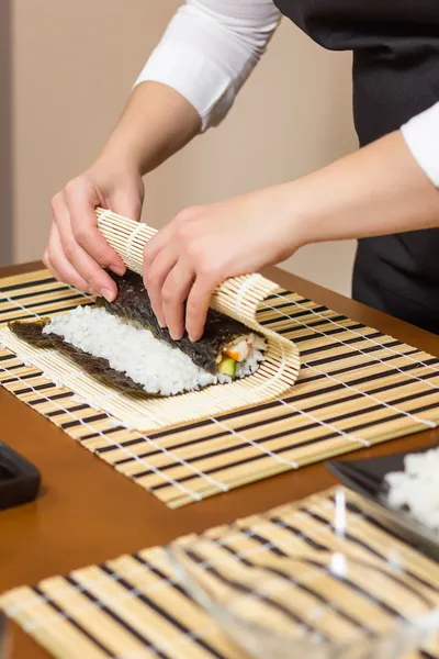 Mâinile unei femei bucătar care rulează un sushi japonez — Fotografie, imagine de stoc