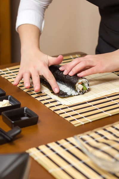 Vrouw hand bevochtigen met water een sushi roll rand — Stockfoto