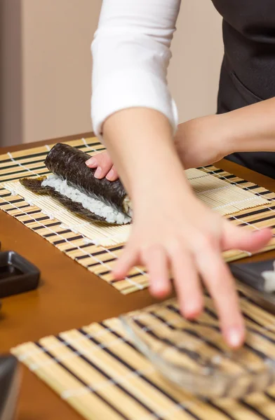 Frau befeuchtet mit Wasser eine Sushi-Rolle — Stockfoto