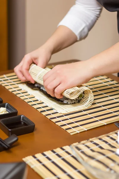 มือของเชฟหญิงกลิ้งขึ้นซูชิญี่ปุ่น — ภาพถ่ายสต็อก