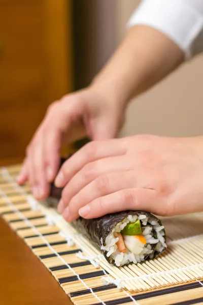 Mains de femme chef enroulant un sushi japonais — Photo