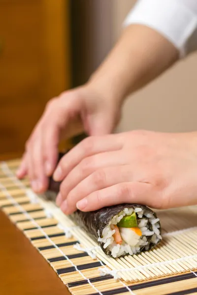 Handen van vrouw chef-kok oprollen van een Japanse sushi — Stockfoto