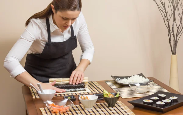 Portret van vrouw chef-kok oprollen van een Japanse sushi — Stockfoto