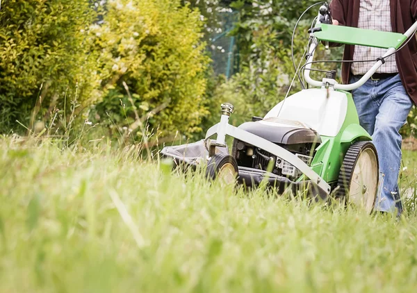 Senior man mowing the lawn with a lawnmower — Stock Photo, Image