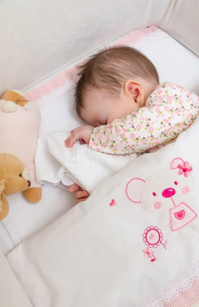 Menina bebê dormindo em um berço com chupeta e brinquedo — Fotografia de Stock