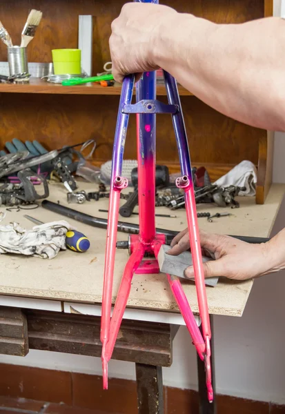 Hands of real bicycle mechanic sanding frame bike — Stock Photo, Image