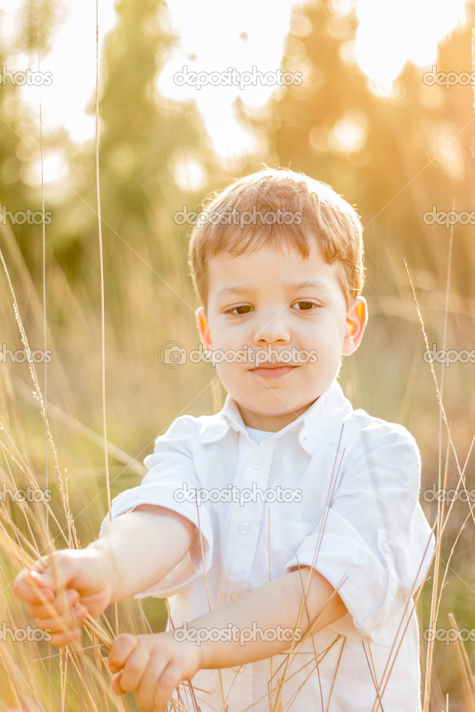 Kid in field playing with spikes at summer sunset