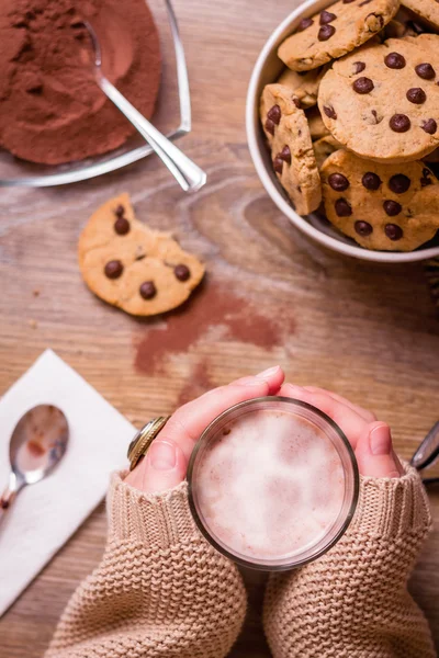 Mani femminili con bevanda calda e biscotti al cioccolato — Foto Stock