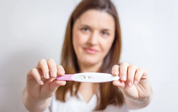 Mujer feliz mostrando su prueba de embarazo positiva — Foto de Stock