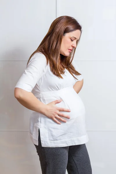 Беременная женщина с сильной болью массирует спину — стоковое фото
