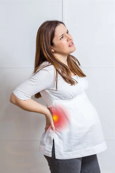 Pregnant woman with strong pain massaging her back — Stock Photo, Image