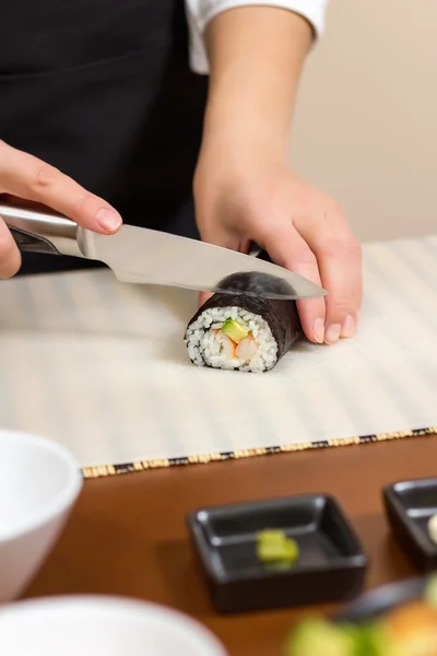 Close-up van vrouw chef-kok snijden Japanse sushi roll — Stockfoto