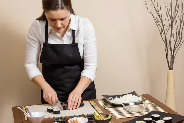 Retrato de mujer chef cortando rollo de sushi japonés —  Fotos de Stock