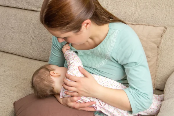 Madre joven amamantando a su bebé en casa — Foto de Stock