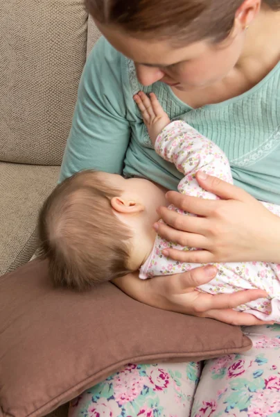 Jovem mãe amamentando seu bebê em casa — Fotografia de Stock