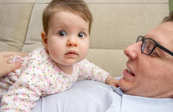 Cute baby playing with her happy father in a sofa — Stock Photo, Image
