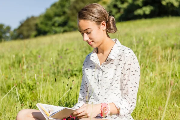 Schöne junge Studentin liest ein Buch im Park — Stockfoto