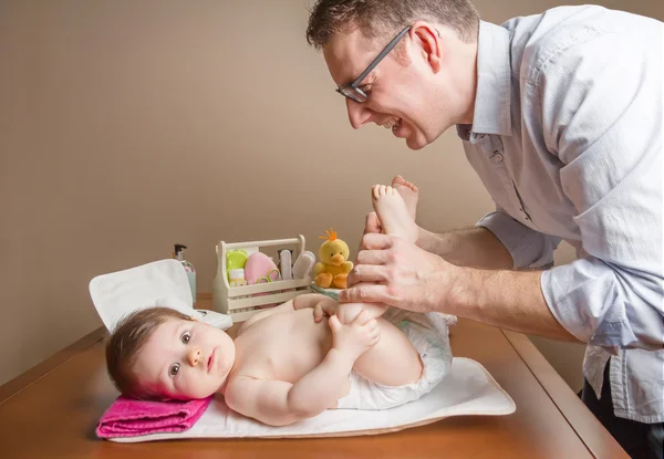Vader spelen met baby voeten na verandering luier — Stockfoto