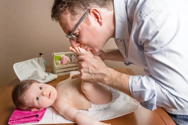 Pai brincando com os pés de bebê após mudar fralda — Fotografia de Stock