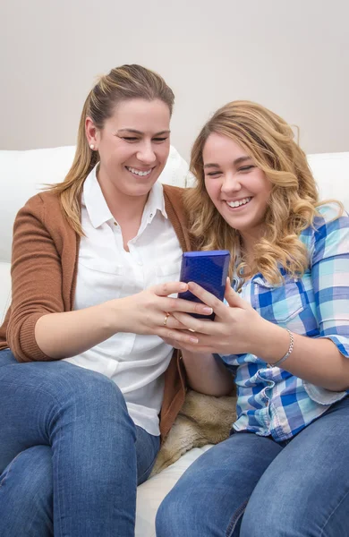 Moeder en dochter lachen wanneer we kijken naar telefoon — Stockfoto