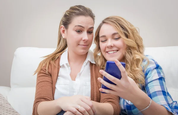 Anne ve kızı telefona bakarken gülüyor — Stok fotoğraf