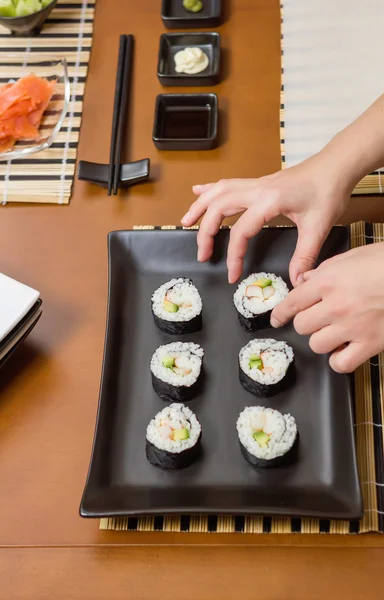 Vrouw chef-kok plaatsen Japanse sushi rolt op een dienblad — Stockfoto