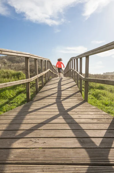 Back view of girl running in a wood boardwalk — Stock Photo, Image