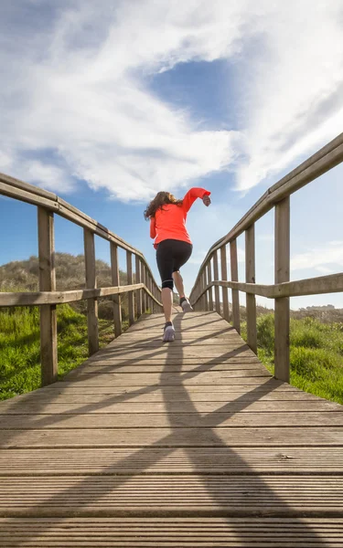 Rückansicht eines Mädchens, das auf einer Holzpromenade läuft — Stockfoto