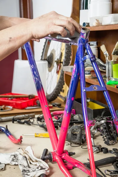 Hands of real bicycle mechanic sanding frame bike — Stock Photo, Image