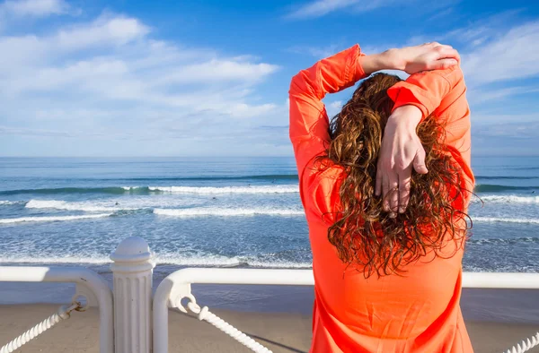 Chica joven calentándose antes de correr en un paseo marítimo — Foto de Stock