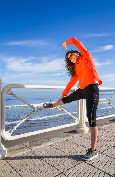 Chica joven calentándose antes de correr en un paseo marítimo —  Fotos de Stock