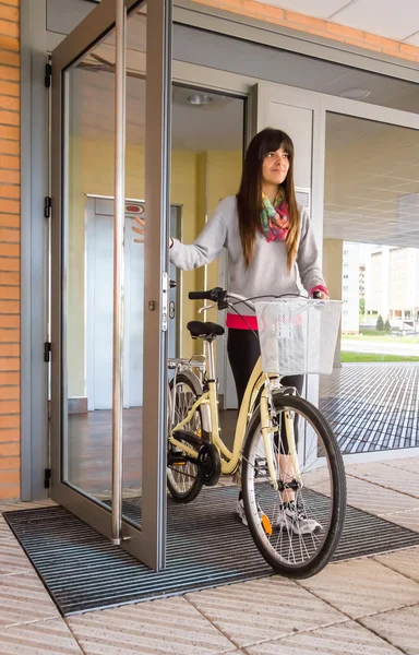 Girl with fixie bike opening a glass door to exit — Stock Photo, Image