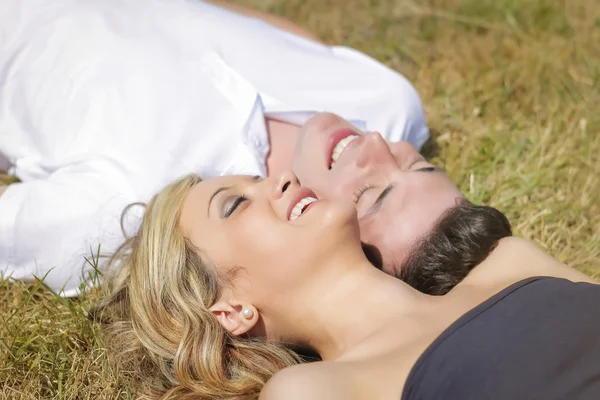 Liefde paar lachen liggen op gras in zomerdag — Stockfoto